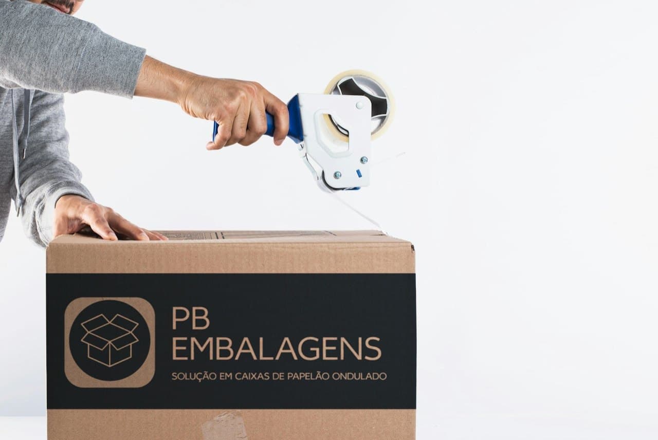 Caixa com a marca PB Embalagens sendo fechada com fita